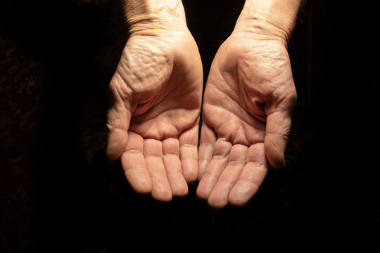 Two hands on a black background. The concept of asking for help.