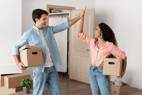 Happy man and woman giving high five celebrating moving day