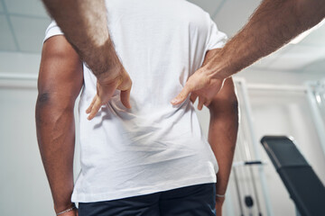 Experienced doctor palpating paralumbar muscles of man
