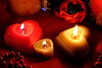 
Fortune-telling on candles, fire and a ring, Russian fortune-telling for love at Christmas. Burning red candles, heart shaped candles, ruby ​​beads on the table.Occult concept. February 14 decoration