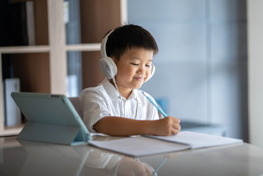 Asian boy study online with digital tablet and headphone. Concept of online studying & home school