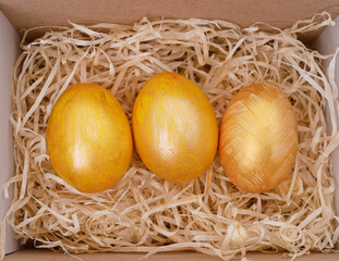 Three golden eggs in a box.