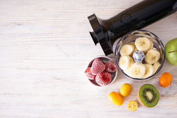Hand blender and accessories with sliced fruit on a wooden background, place for text. Top view.