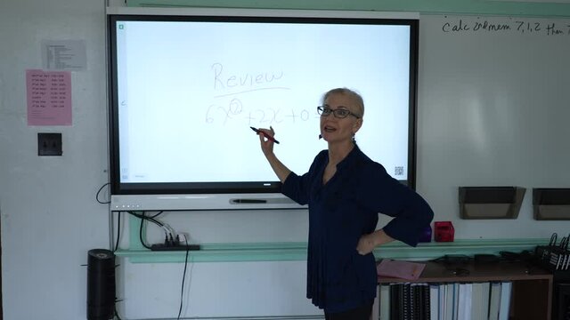 Slow motion of female teacher writing on an interactive whiteboard in an empty classroom.