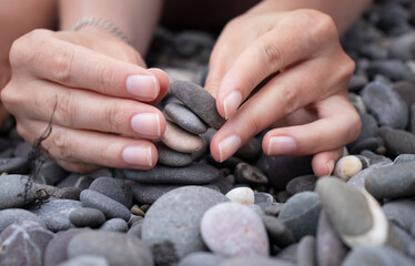 girl collects a cairn of stones by the sea in summer