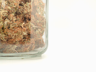 Dry cannabis buds flower in a jar glass on the table isolated on a white background