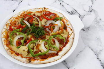 Freshly made pizza with meat and vegetable toppings