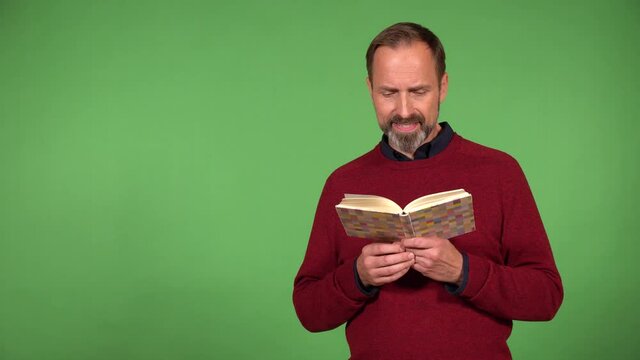 A middle-aged handsome Caucasian man reads a book - green screen background
