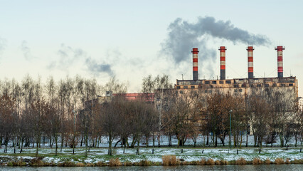 Obraz premium Industrial air pollution. Winter landscape with factory and trees. The concept of environmental pollution.