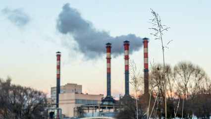 Obraz premium Industrial air pollution. Winter landscape with factory and trees. The concept of environmental pollution.