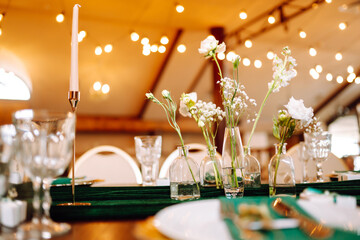 Floral decorations on the banquet table in the restaurant. The work of professional florists in emerald color. Wedding, birthday, party, event concept.