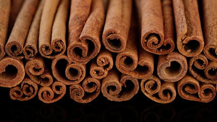 Cinnamon sticks on black background. Heap of cinnamon sticks.