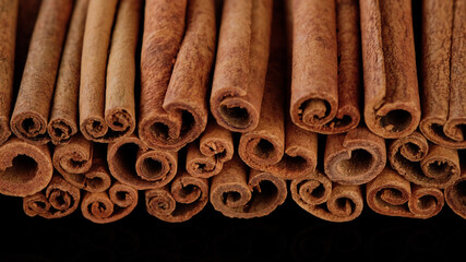 Cinnamon sticks on black background. Heap of cinnamon sticks