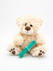 Teddy bear with plastic syringe - children soft toy on white background