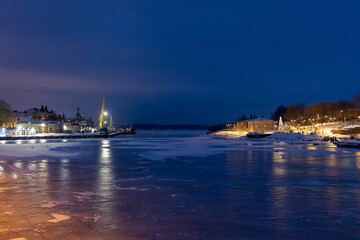 The port of Vyborg at night in winter with frozen water in the bay.