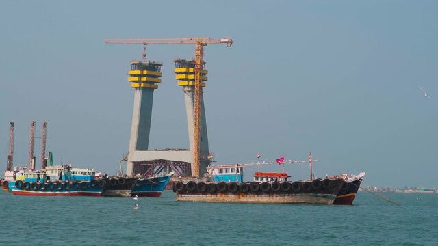 Boat in the sea moving in front of the Signature cable bridge under construction between Okha and Beyt Dwarka at Gujarat, India