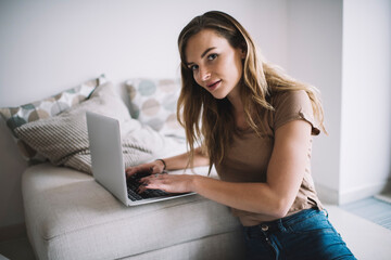 Portrait of young Caucasian freelancer with laptop computer looking at camera during remote working...