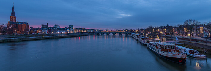 panoramic image of the skyline of Maastricht during the blue hour with views on the Sint Servaas bridge, the boat company for day trips and trendy neighborhood Wyck