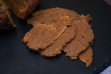 Home made seitan ham and thin  seitan slices on slate board