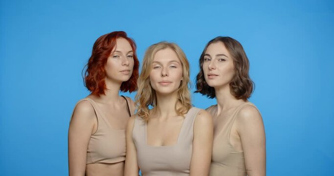 Blonde, redhead and dark haired woman are looking and smiling to the camera, portrait of different types of women in the blue screen, 4k 24p Prores