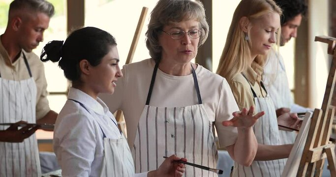 Middle aged teacher of art school explain new technique perspective theories to attentive Indian female student. Focused young woman artist beginner listen to advices of experienced older colleague