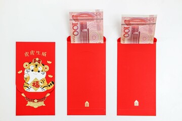 Three Chinese New Year Lucky red envelopes with 100 Chinese yuan inside, laid out on white background