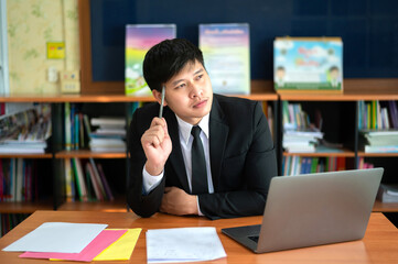 To find inspiration.Young businessman thinking, using  computer and looks away while sitting at his workplace in the office.