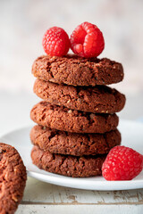 Oatmeal cookies with raspberries on bright background.