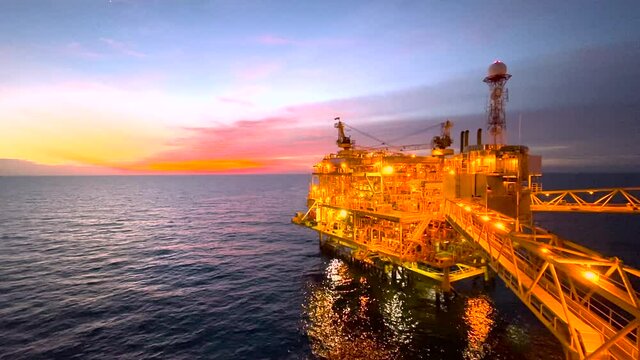 offshore oil and gas platform in sunset time the platform produced raw gases and crude oil for sent to onshore refinery, petrochemical plant and tanker for export for industry concept.