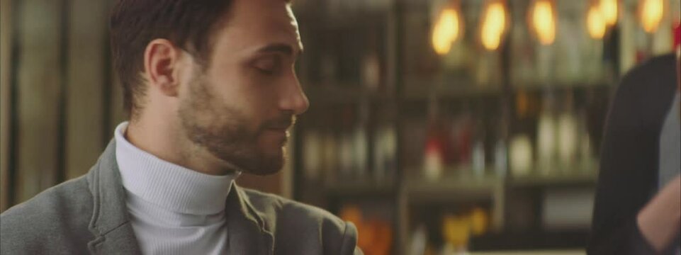 Mid adult Caucasian man attaching mobile phone to wireless terminal. Using modern contactless payment method for paying in cafe.