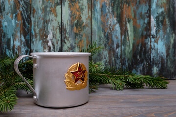 Old aluminum retro cup with the symbols of the Soviet army on a wooden table. Metal cup.
