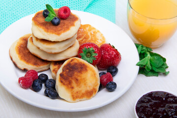 Cottage cheese pancakes with berries on a white plate on the table