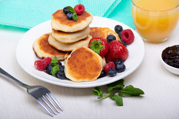 Cottage cheese pancakes with berries on a white plate on the table