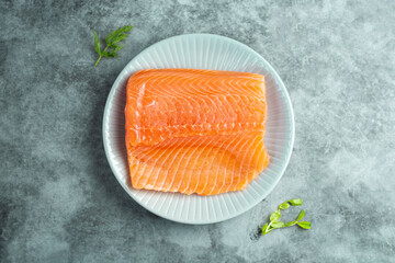 Fresh salmon fillet in a plate, top view. gray background.