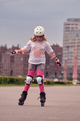 A child of ten is rollerblading in the park. The girl is wearing fall protection. Roller skating around the city. - obrazy, fototapety, plakaty