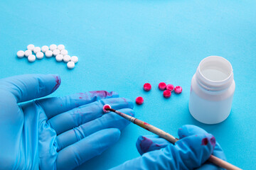 Counterfeiting drugs. Gloved hands counterfeiting pills. - obrazy, fototapety, plakaty