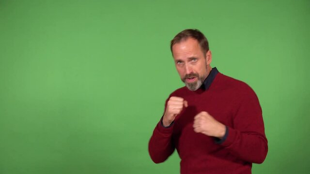 A middle-aged handsome Caucasian man boxes the camera - green screen background