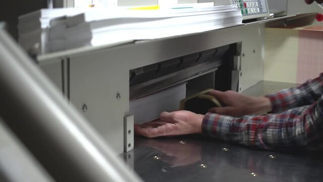 Modern cutting paper machine, papper guillotine cutter in work, printing company. Industry printing equipment 