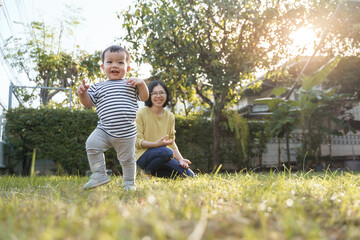Fototapeta premium Portrait of Smiling Asian Little child son and his young mother in nature with sunlight, Happy family home.