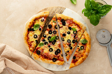 Homemade pizza ham, black olives, cheese and fresh basil. Sourdough pizza.