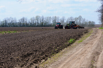 red and green tractor in a field, tractor planting crops on an agricultural field. tractor working in the field, harvesting, business, agriculture. soil preparation, spring season. farming in Ukraine