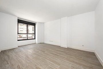 empty room recently painted in white with black aluminum window and ceramic floors similar to wood