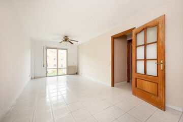Living room empty of furniture with glazed terrace, lamp with fan and wooden carpentry