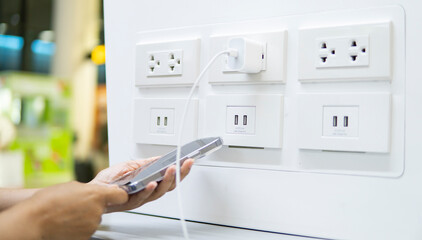 people holding smartphone and chart battery on battery charger station of airport