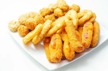 Southern fried and roast chicken bites, onion rings and mozzarella stick served on the white plate