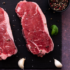 Top down close up view of a raw striploin steak with seasoning.