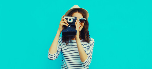 Summer portrait of happy smiling young woman photographer with vintage film camera on colorful blue background