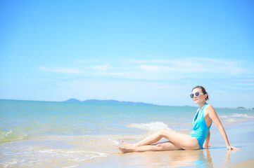 Fototapeta na wymiar Woman enjoying beach relaxing joyful in summer by tropical blue water. model on travel wearing sun glasses.