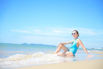 Fototapeta na wymiar Woman enjoying beach relaxing joyful in summer by tropical blue water. model on travel wearing sun glasses.