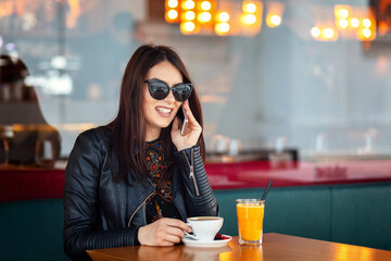 Smiling young woman talking on cell phone at bar table